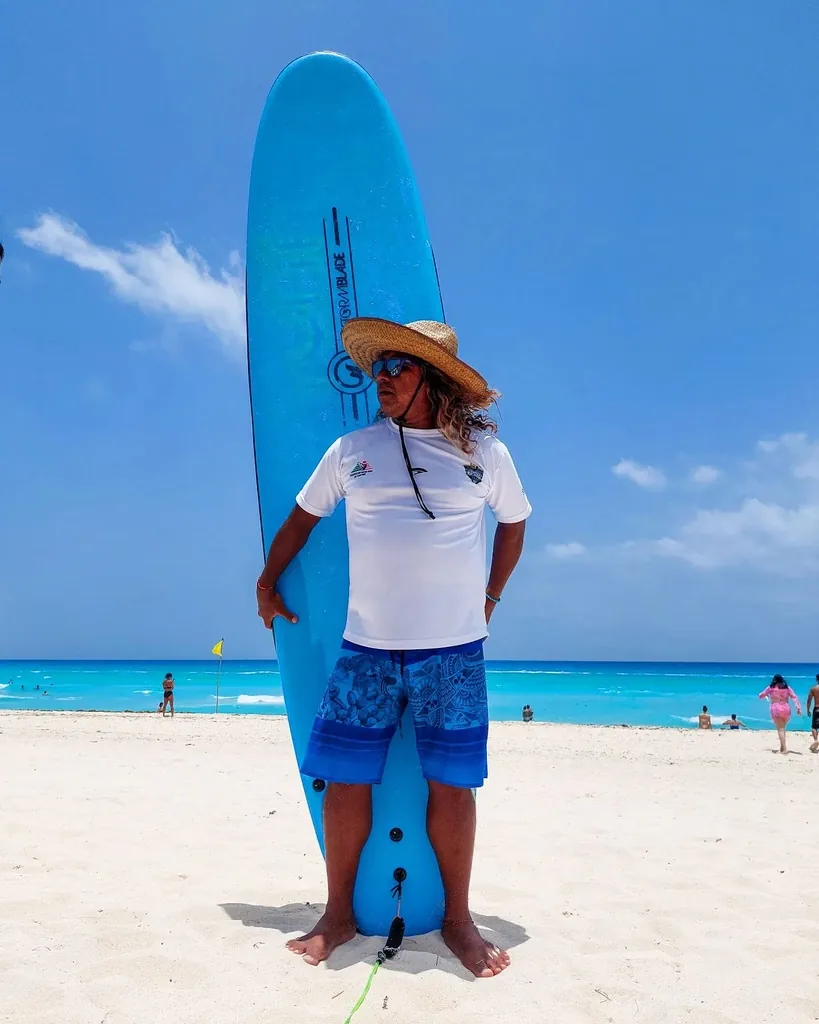 David Jamaican Hernández con una tabla de surf en Playa Delfines.