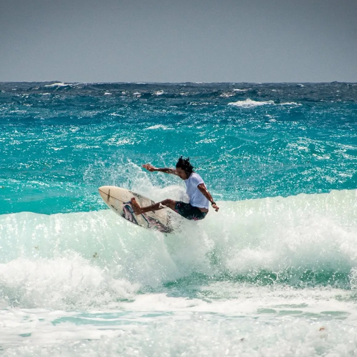 A surfer working on an advanced maneuver at Playa Delfines.